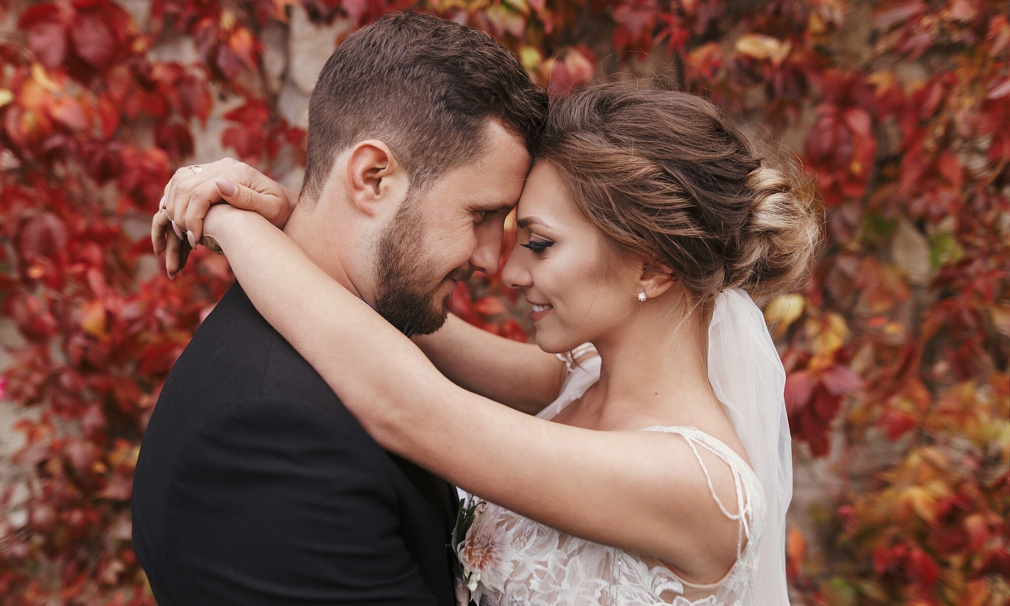 Matrimonio autunnale, sposo e sposa con fondo di foglie rosse